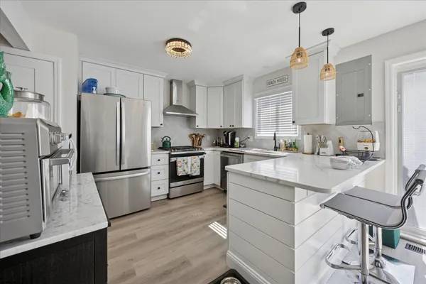 a kitchen with a refrigerator a sink dishwasher and white cabinets with wooden floor