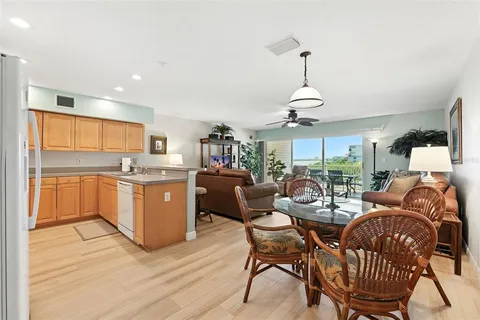a very nice looking open dining room with kitchen island stainless steel appliances wooden floor and a chandelier