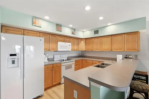 a kitchen with a sink a stove a refrigerator a counter top space and cabinets