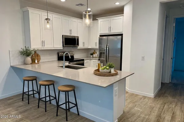 a room with lots of white furniture a chandelier and a flat screen tv