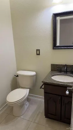 a bathroom with a granite countertop toilet sink and mirror