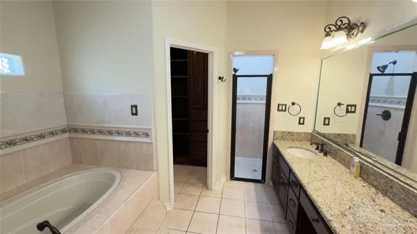 a spacious bathroom with a granite countertop tub sink and mirror