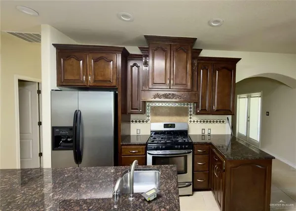 a kitchen with stainless steel appliances granite countertop a refrigerator a stove and a sink