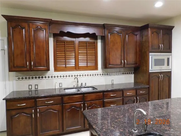 a kitchen with granite countertop a sink and a refrigerator