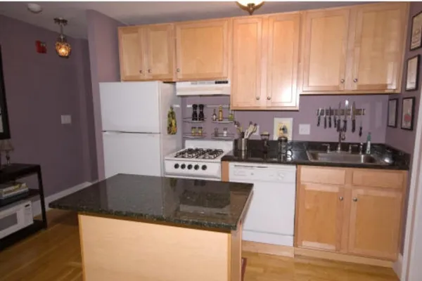 a kitchen with granite countertop a refrigerator a stove a sink and dishwasher with wooden floor