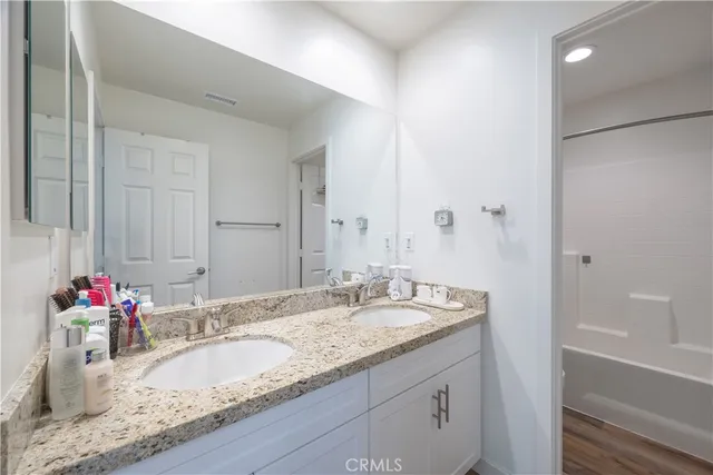 a bathroom with a granite countertop double vanity sink and a mirror