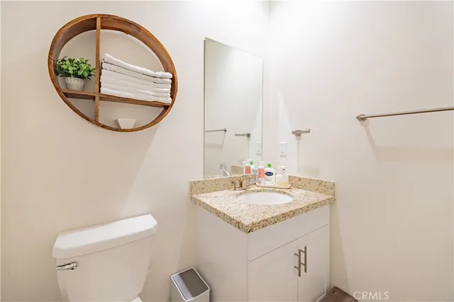 a bathroom with a granite countertop toilet a sink and a mirror