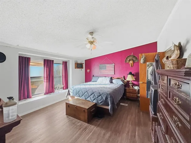 a spacious bedroom with a bed and wooden floor