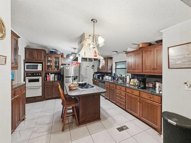 a kitchen with stainless steel appliances granite countertop a stove top oven a dining table and chairs with wooden floor