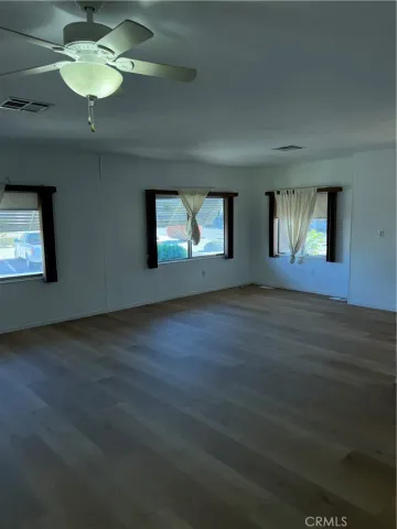 a view of an empty room with window and wooden floor