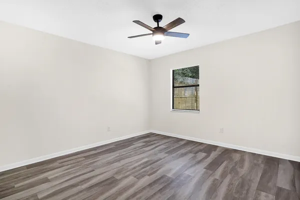 an empty room with wooden floor and ceiling fan