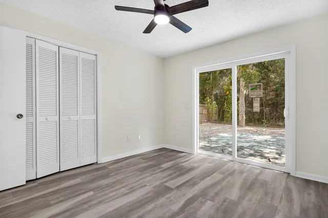a view of empty room with wooden floor and fan