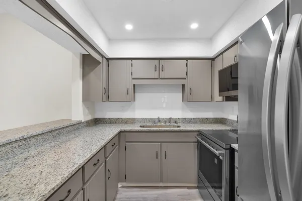 a kitchen with stainless steel appliances granite countertop a sink stove and refrigerator