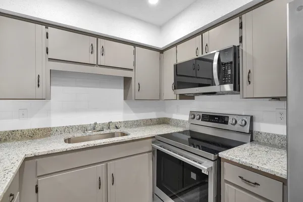 a kitchen with stainless steel appliances granite countertop a sink stove and microwave