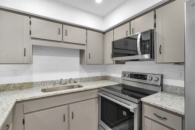 a kitchen with stainless steel appliances granite countertop a sink stove and microwave