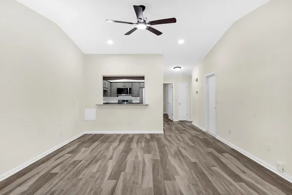 a view of empty room with wooden floor and ceiling fan