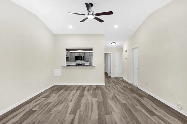 a view of empty room with wooden floor and ceiling fan