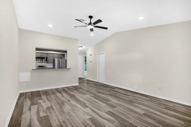 a view of empty room with wooden floor and ceiling fan