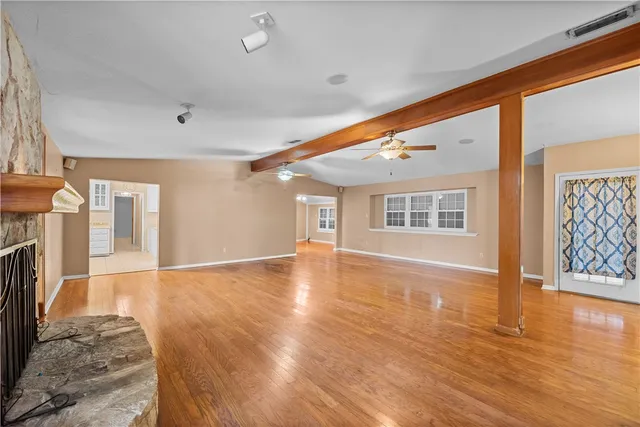 a view of an empty room with wooden floor and a fireplace