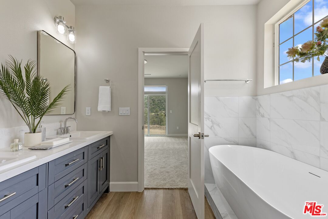 28701 Delaware Drive Tehachapi, CA 93561 - Photo 11 of 15 a bathroom with a granite countertop sink a large mirror a bathtub and shower