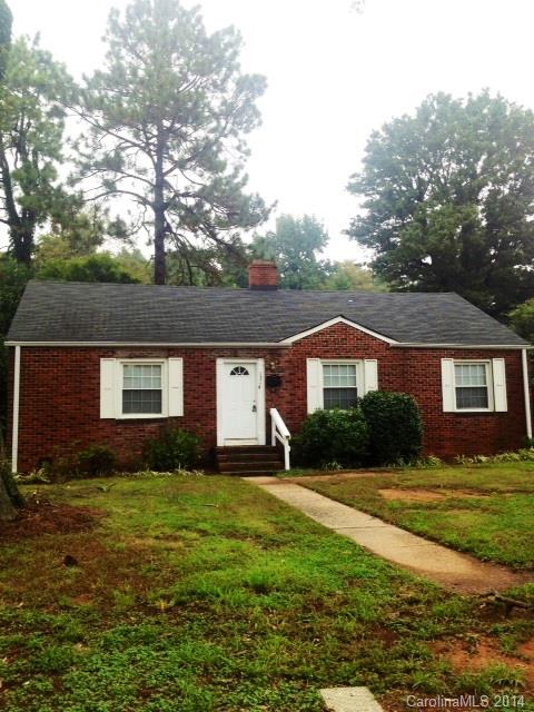 a front view of house with yard and trees in the background