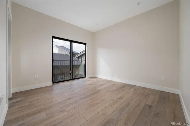 a view of an empty room with wooden floor and closet