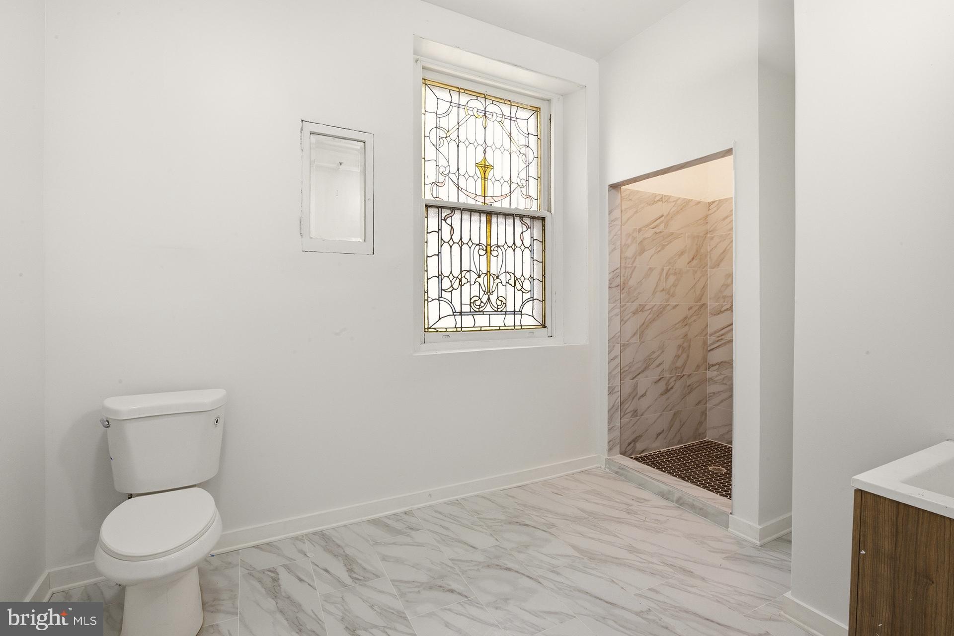 6012 Ridge Avenue, Unit 5 Philadelphia, PA 19128 - Photo 8 of 19 a bathroom with a toilet a sink and a window