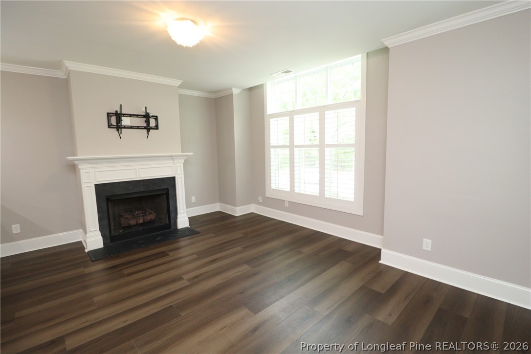 2824 Plumfield Place Raleigh, NC 27607 - Photo 13 of 33 a view of an empty room with wooden floor fireplace and a window