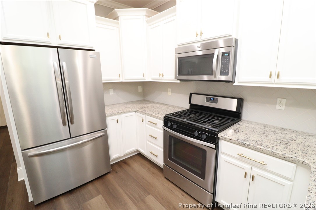 2824 Plumfield Place Raleigh, NC 27607 - Photo 10 of 33 a kitchen with stainless steel appliances white cabinets and wooden floor
