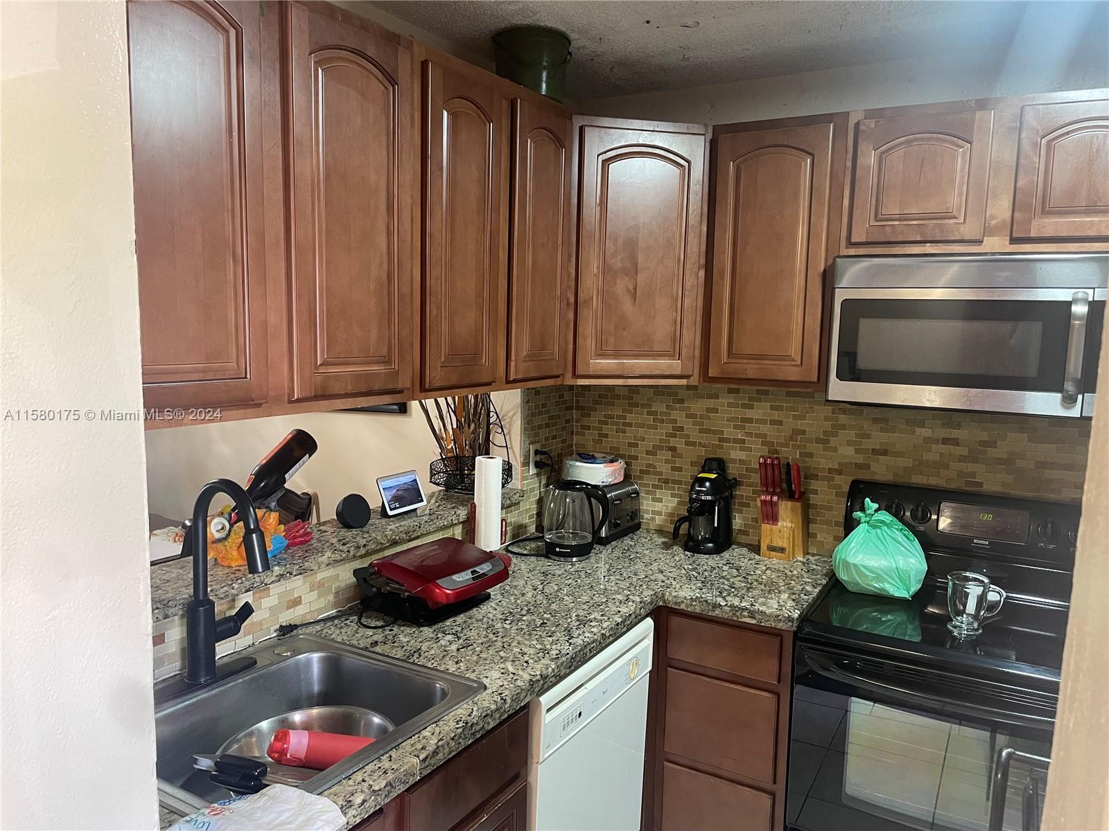 3252 Foxcroft Road, Unit 208 Miramar, FL 33025 - Photo 3 of 13 a kitchen with stainless steel appliances granite countertop a sink stove and cabinets