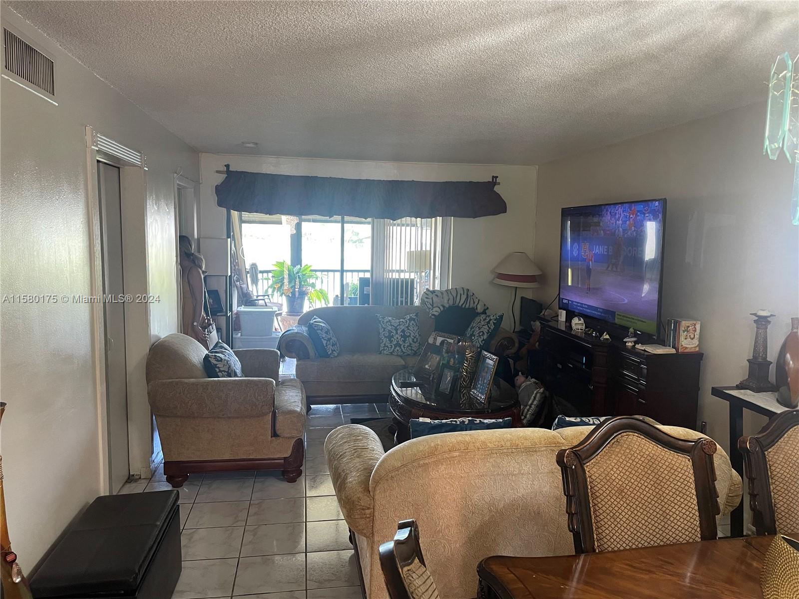 3252 Foxcroft Road, Unit 208 Miramar, FL 33025 - Photo 4 of 13 a living room with furniture and a flat screen tv