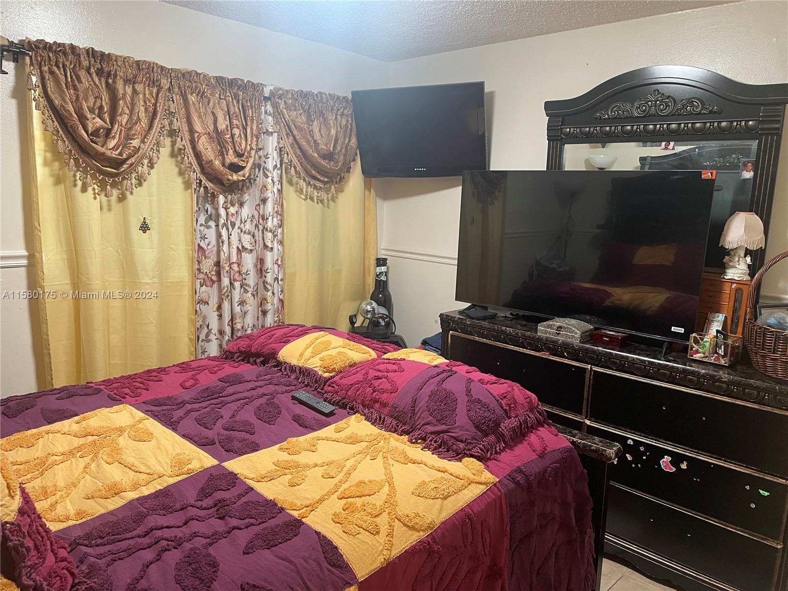3252 Foxcroft Road, Unit 208 Miramar, FL 33025 - Photo 5 of 13 a bedroom with a bed and a flat tv screen