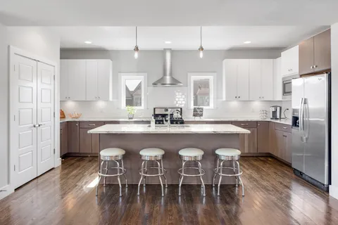 a kitchen with stainless steel appliances granite countertop a dining table chairs refrigerator sink and cabinets