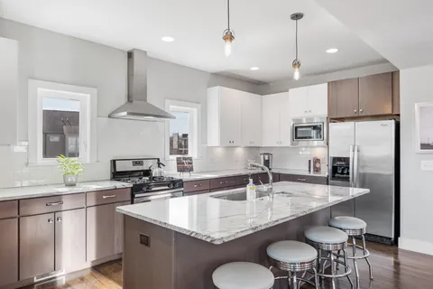 a kitchen with granite countertop a sink a center island stainless steel appliances and cabinets