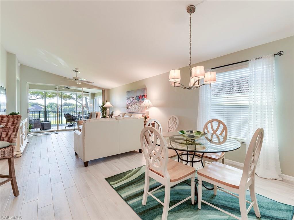 9010 Spring Run Boulevard, Unit 702 Estero, FL 34135 - Photo 11 of 35 a dining room filled chandelier and wooden floor