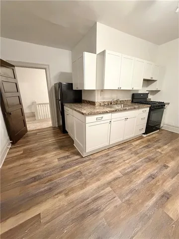 a kitchen with granite countertop a sink stainless steel appliances and white cabinets