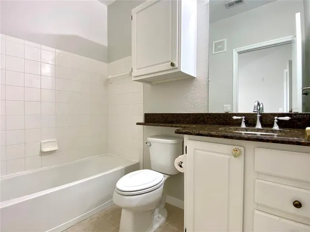 a bathroom with a granite countertop toilet a sink and bathtub
