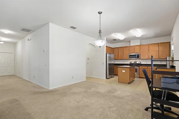 a kitchen with stainless steel appliances kitchen island granite countertop a table chairs and a refrigerator