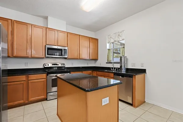 a kitchen with granite countertop a sink stove and microwave