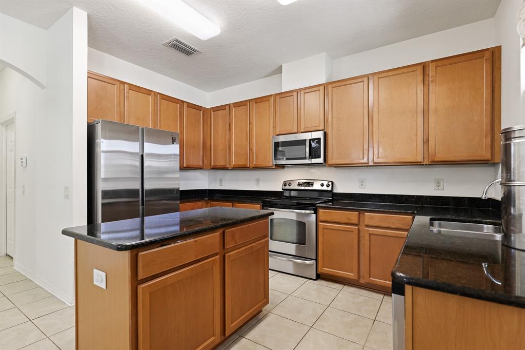 1411 Main Street Valrico, FL 33594 - Photo 16 of 44 a kitchen with kitchen island granite countertop a stove top oven a sink a counter space and cabinets