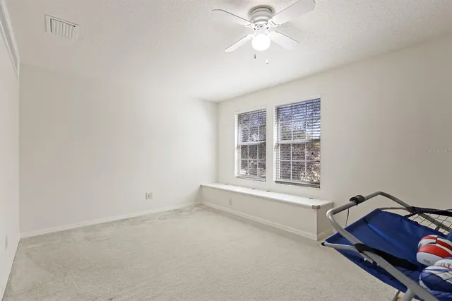 an empty room with windows and fan