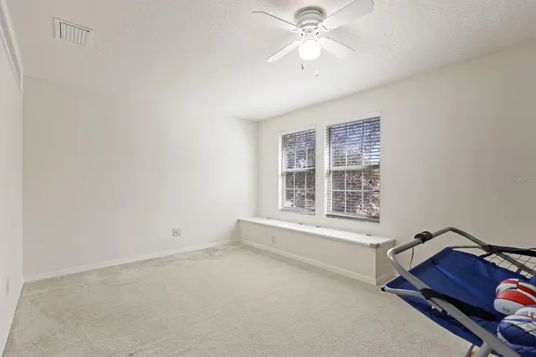 an empty room with windows and fan