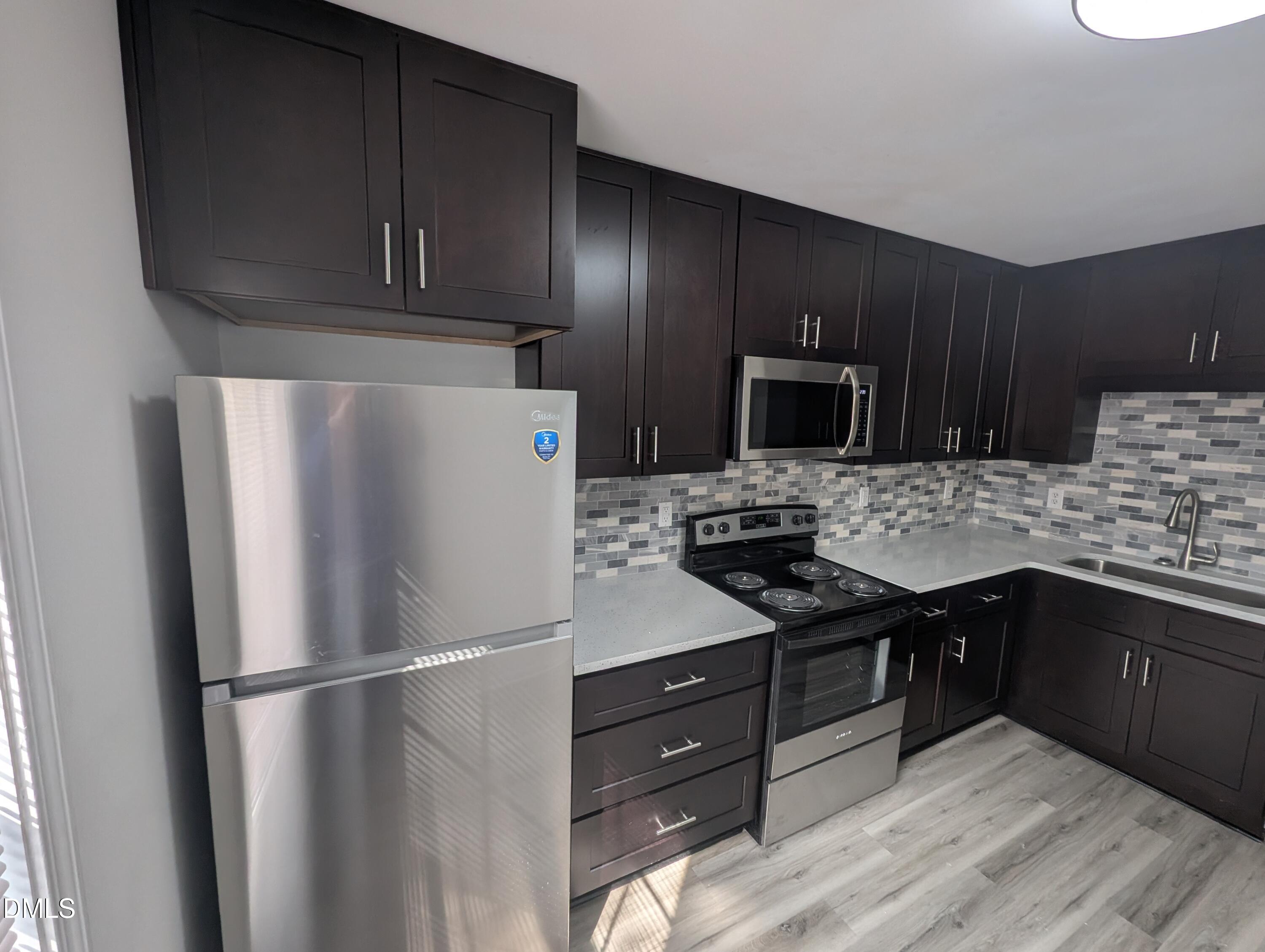 1005 Shades Place Raleigh, NC 27601 - Photo 7 of 18 a kitchen with granite countertop a refrigerator stove and microwave