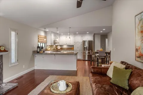 a living room with stainless steel appliances kitchen island granite countertop furniture and a wooden floor