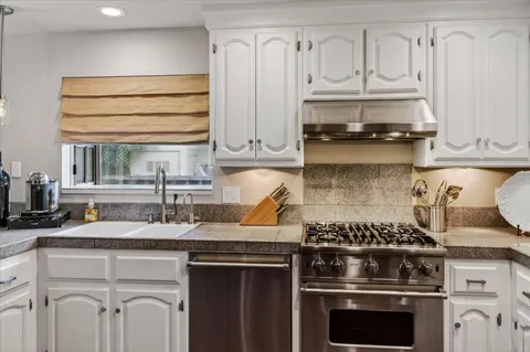 a kitchen with granite countertop a stove sink and cabinets