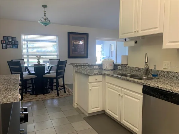 a kitchen with kitchen island granite countertop a table chairs sink and cabinets