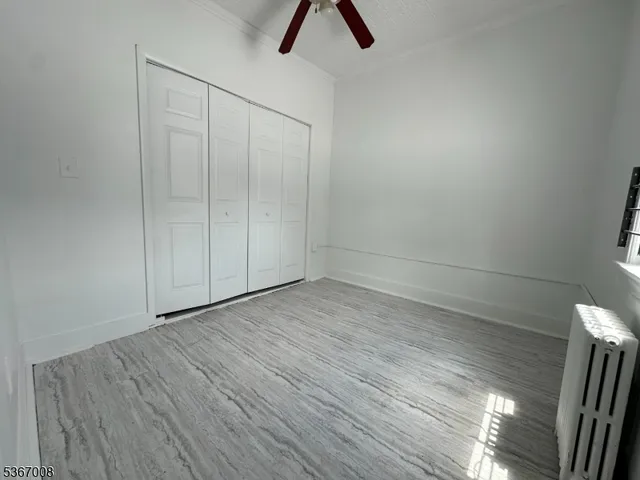 a view of an empty room with wooden floor and window
