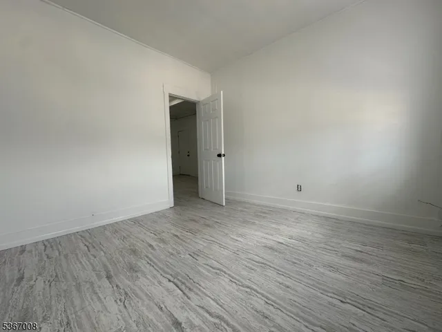 a view of an empty room with wooden floor and closet