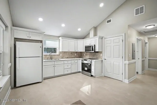 a kitchen with white cabinets and white appliances