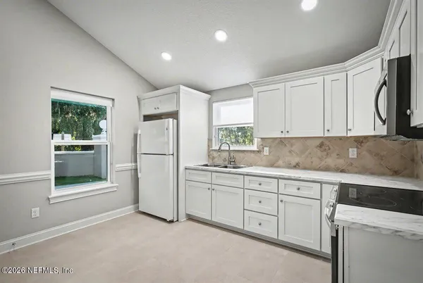 a kitchen with white cabinets and white appliances